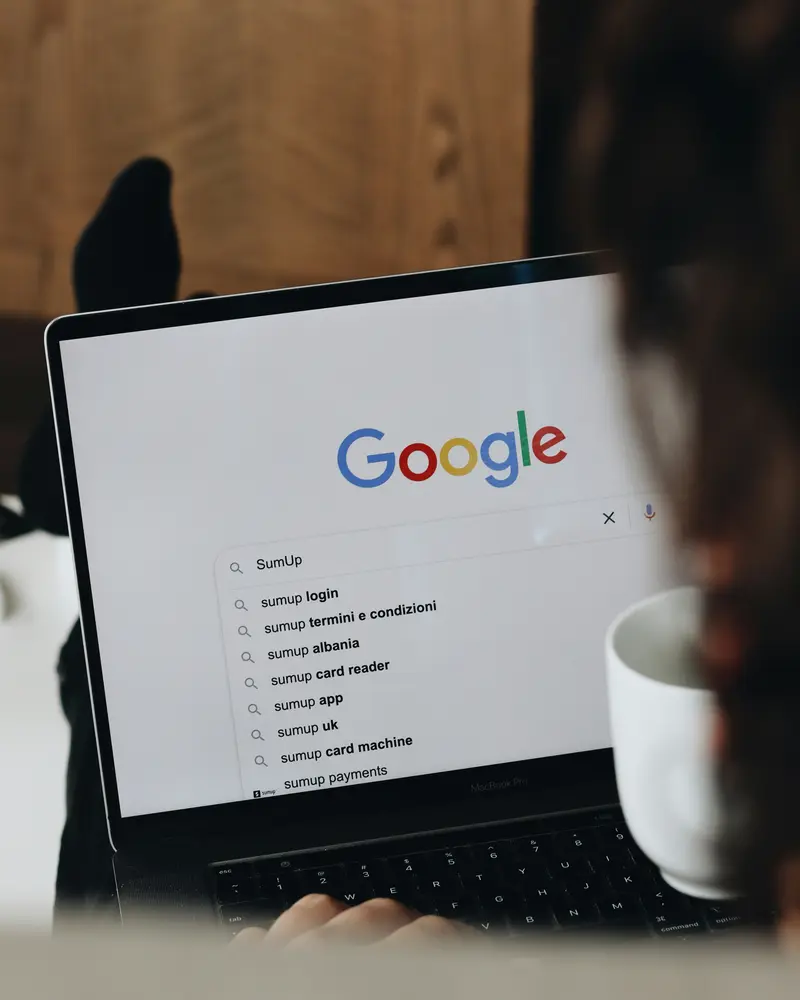 Une recherche Google ouverte sur un ordinateur portable, à côté d'un café