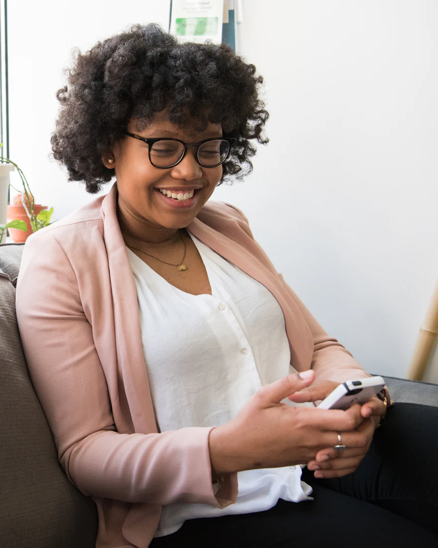 Une femme sourit en regardant son téléphone